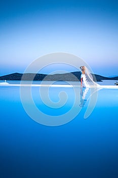 Beautiful bride blonde female model in amazing wedding dress poses on the island of Santorini