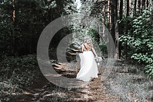 Beautiful bride blonde running through the woods alone.