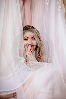 Beautiful bride blonde woman sitting near vintage wardrobe full of wedding dresses. fashion beauty portrait