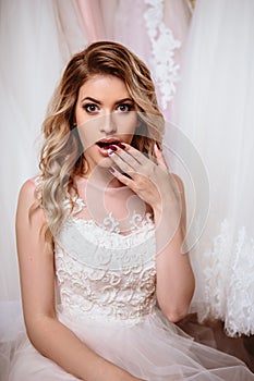 Beautiful bride blonde woman sitting near vintage wardrobe full of wedding dresses. fashion beauty portrait