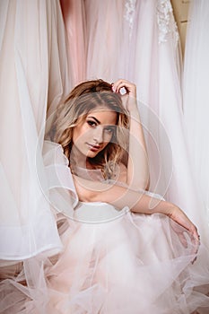 Beautiful bride blonde woman sitting near vintage wardrobe full of wedding dresses. fashion beauty portrait