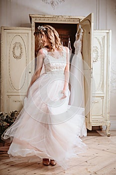 Beautiful bride blonde woman sitting near vintage wardrobe full of wedding dresses. fashion beauty portrait