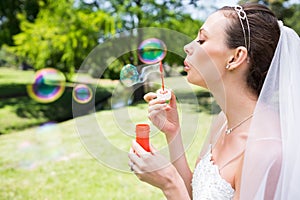 Beautiful bride blowing bubbles in garden