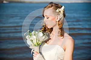 Beautiful bride with a bouquet of calla lilies on coast of river