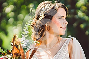 Beautiful bride with bouquet flowers stands on forest background. Rustic style. beautiful bride in delicate dress outdoors. Close