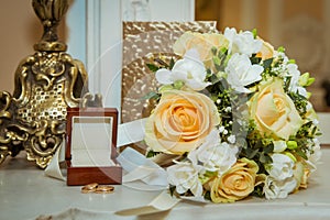 Beautiful bride bouquet with yellow roses, white flowers and gold rings with a crust on the wedding day