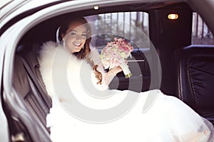 Beautiful bride with bridal bouquet in car on wedding day