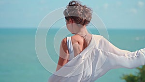 Beautiful bride dances against the sea on her wedding day