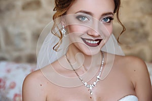 A beautiful bride and a dress with open shoulders. A close-up shot of a girl with a delicate eye makeup and red lips