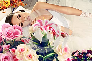 Beautiful bride in elegant wedding dress posing among flowers