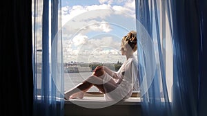 Beautiful bride in front of a window. Bride looking through the window. Bride near the window. Happy Bride looking in