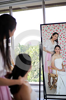 Beautiful bride getting dressed by her best friend in her wedding day and choosing a wedding dress in the shop and the shop