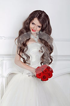 Beautiful bride girl with red roses bouquet posing in modern int