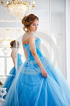 Beautiful bride in gorgeous blue dress Cinderella style near mirror