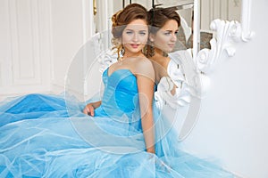 Beautiful bride in gorgeous blue dress Cinderella style near mirror