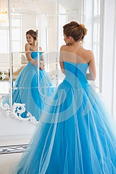 Beautiful bride in gorgeous blue dress Cinderella style near mirror