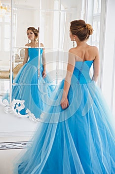 Beautiful bride in gorgeous blue dress Cinderella style near mirror