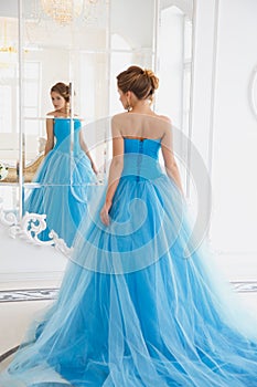 Beautiful bride in gorgeous blue dress Cinderella style near mirror