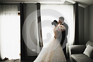 Beautiful bride and groom embracing and kissing on their wedding day