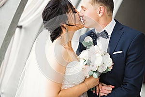 Beautiful bride and groom embracing and kissing on their wedding day