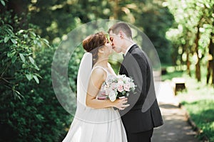 Beautiful bride and groom embracing and kissing on their wedding day