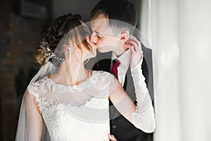 Beautiful bride and groom embracing and kissing on their wedding day