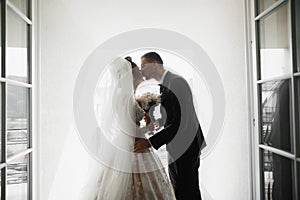 Beautiful bride and groom embracing and kissing on their wedding day