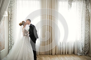 Beautiful bride and groom embracing and kissing on their wedding day