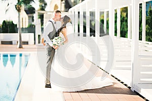 Beautiful bride and groom embracing and kissing on their wedding day