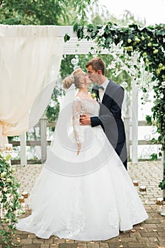 Beautiful bride and groom embracing and kissing on their wedding day