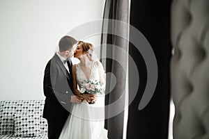 Beautiful bride and groom embracing and kissing on their wedding day