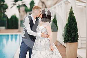 Beautiful bride and groom embracing and kissing on their wedding day