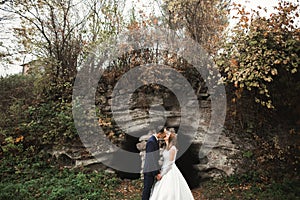 Beautiful bride and groom embracing and kissing on their wedding day outdoors