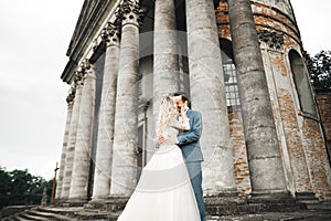 Beautiful bride and groom embracing and kissing on their wedding day outdoors