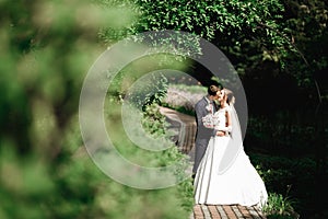 Beautiful bride and groom embracing and kissing on their wedding day outdoors