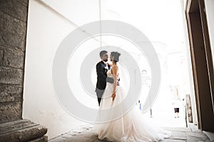 Beautiful bride and groom embracing and kissing on their wedding day outdoors