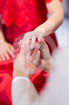 Beautiful bride and groom hands exchanging wedding rings in chur