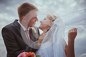 Beautiful bride and groom standing in grass and kissing. Wedding couple fashion shoot.