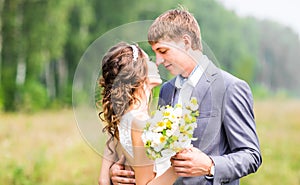 Beautiful bride and groom standing in grass and kissing. Wedding couple