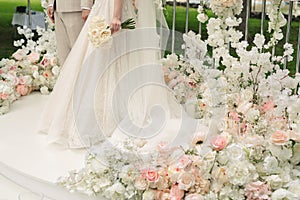 Beautiful bride and groom in the wedding ceremony area of live white and pink flowers.