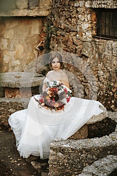 Beautiful bride with her bouquet sititng in the garden