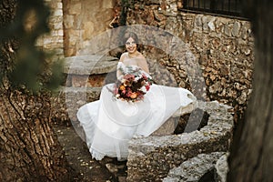 Beautiful bride with her bouquet sititng in the garden
