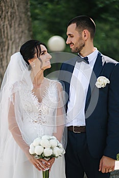 Beautiful bride with her handsome groom walking outside on theri wedding day. Happy newlyweds