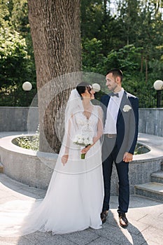 Beautiful bride with her handsome groom walking outside on theri wedding day. Happy newlyweds