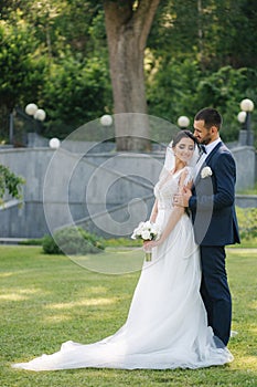 Beautiful bride with her handsome groom walking outside on theri wedding day. Happy newlyweds