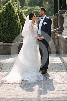 Beautiful bride with her handsome groom walking outside on theri wedding day. Happy newlyweds