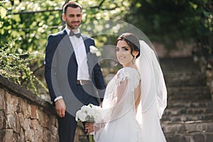 Beautiful bride with her handsome groom walking outside on theri wedding day. Happy newlyweds