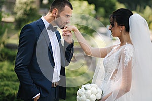 Beautiful bride with her handsome groom walking outside on theri wedding day. Happy newlyweds