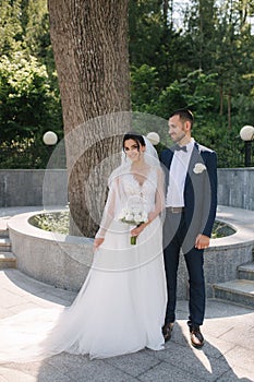 Beautiful bride with her handsome groom walking outside on theri wedding day. Happy newlyweds