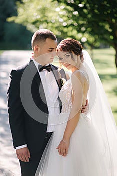 Beautiful bride with her handsome groom walking outside on theri wedding day. Happy newlyweds